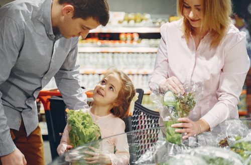 A family enjoys shopping for fresh produce together in a supermarket, smiling and bonding.