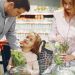 A family enjoys shopping for fresh produce together in a supermarket, smiling and bonding.